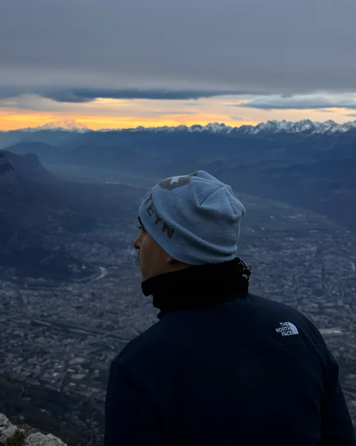 Arthur Pahon, de dos, face aux montagnes au lever du jour